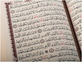 Open Arabic Quran showing decorative calligraphy and traditional border design.