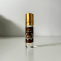 Al Oud perfume oil in a clear glass bottle with gold cap on plain background