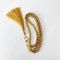 Gold Islamic prayer beads with tassel and crescent moon charm on white background