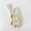 White Islamic prayer beads with pearl design, gold accents, and a decorative tassel
