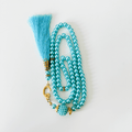 Turquoise Islamic prayer beads with tassel and gold accents on a white background