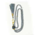 Islamic silver prayer beads with gold accents and a decorative tassel on a white background