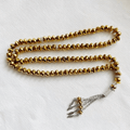 Gold Islamic tasbih prayer beads with faceted beads and silver tassel on white background