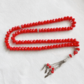 Red Islamic prayer beads tasbih with silver accents on white background